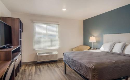 a bedroom with a bed and a flat screen tv at WoodSpring Suites Ashland - Richmond North in Ashland