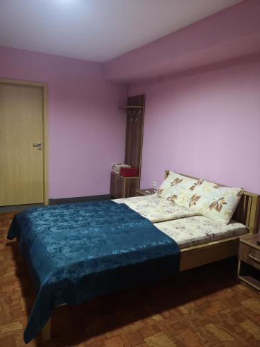 a bedroom with a bed with a blue blanket on it at Pensiunea Mikelis International in Curtea de Argeş