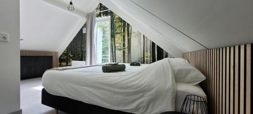 a bedroom with a large white bed with a window at Evergreen wellness met sauna & hottub in Ewijk