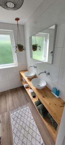 een badkamer met 2 wastafels en een spiegel bij Evergreen wellness met sauna & hottub in Ewijk