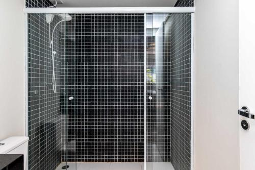 a bathroom with a shower with black tiles at 360 Praça da Árvore in Sao Paulo