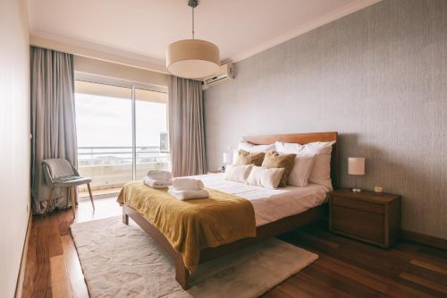 a bedroom with a large bed and a large window at By the Sea II - calmo com piscina e vista mar. in Funchal