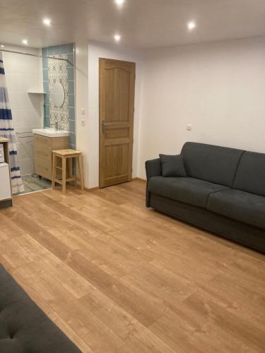 a living room with a couch and a wooden floor at Un studio dans notre chalet in La Plagne Tarentaise