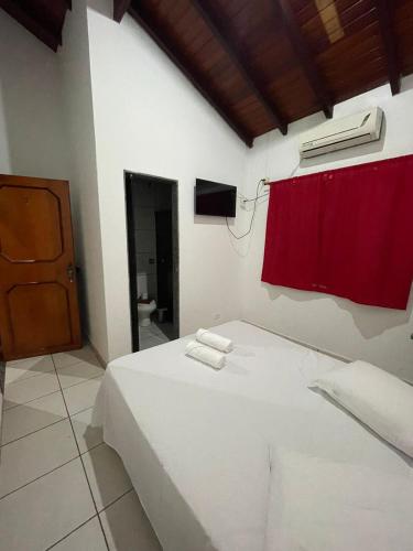 sypialnia z białym łóżkiem z czerwoną zasłoną w obiekcie HOTEL MARAMBAIA w mieście Ponta Porã
