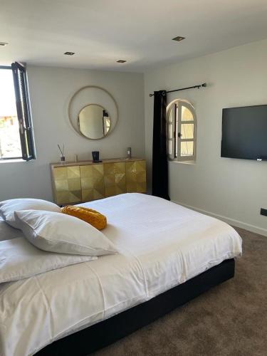 - une chambre avec un grand lit blanc et une télévision à écran plat dans l'établissement Domaine des Oliviers, à Saint-Savin