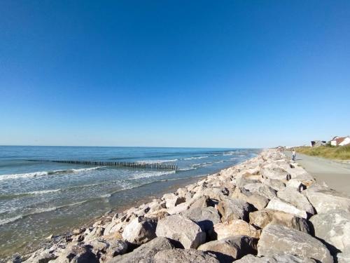 uma praia rochosa com um cais e o oceano em Le Clos des Mouettes em Calais