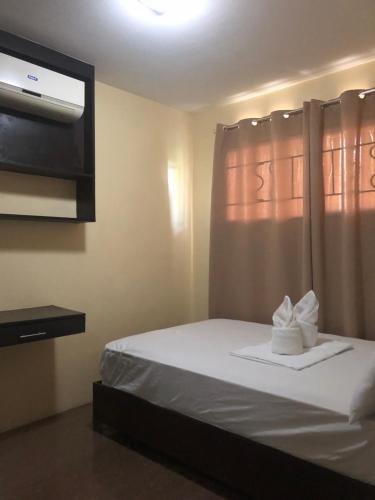 a bedroom with a white bed with a tv on the wall at Alles One Oasis Condo Davao Near SM Mall with Wifi in Davao City