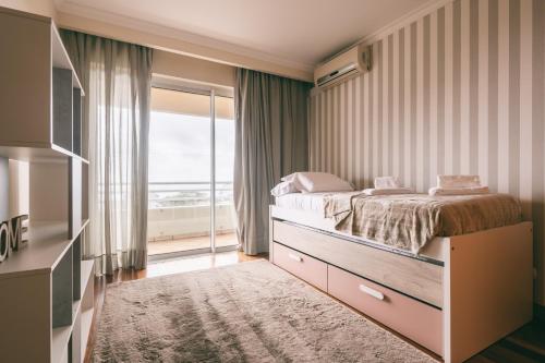 a bedroom with a bed and a large window at By the Sea II - calmo com piscina e vista mar. in Funchal