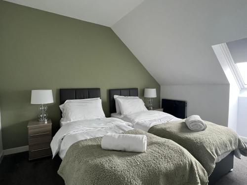 1 dormitorio con 2 camas, sábanas blancas y toallas en Dunbar High Street One Bedroom Apartment, en Dunbar