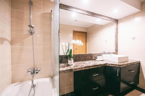 a bathroom with a tub and a sink and a shower at By the Sea II - calmo com piscina e vista mar. in Funchal