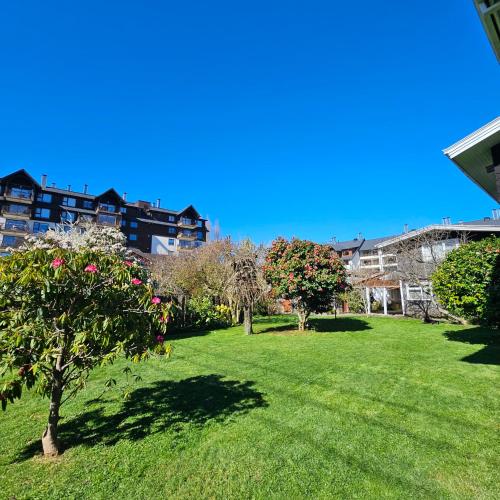 a park with trees and grass and buildings at Casa Ellies Hotel Boutique in Puerto Varas