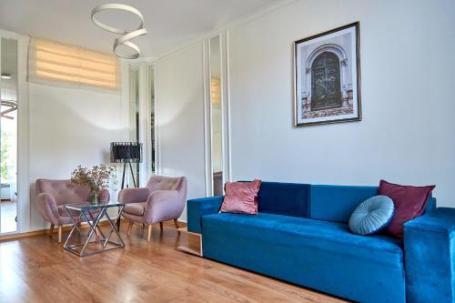 sala de estar con sofá azul y sillas rosas en Стильні Апартаменти на Ратушній площі, en Mukácheve