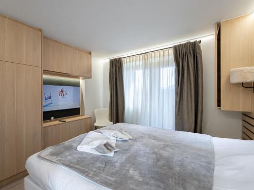 a hotel room with a bed and a flat screen tv at Appartement Courchevel 1850, 3 pièces, 6 personnes - FR-1-564-80 in Courchevel