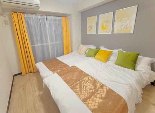 大阪的住宿－난바역 앞 편안한 숙소 f501，一间卧室配有一张大床,提供黄色和绿色的枕头
