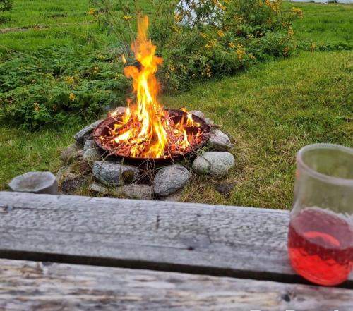a fire pit with a glass of wine next to it at Warm and cozy cottage, Great location in Kvaløya