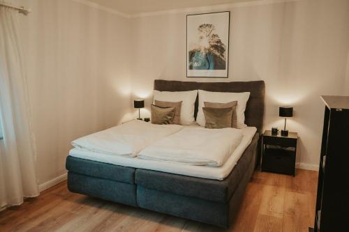 Schlafzimmer mit einem Bett mit weißer Bettwäsche und Kissen in der Unterkunft WITTMANN Ganze Apartments in Gifhorn in Gifhorn