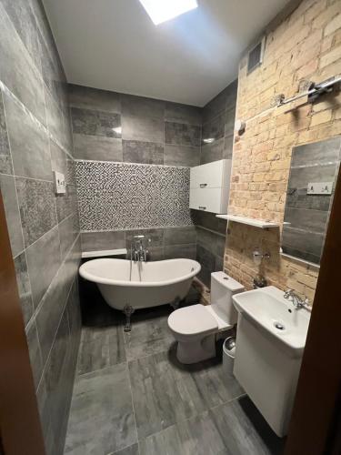 a bathroom with a sink and a tub and a toilet at Apartamenty Dekora in Żary