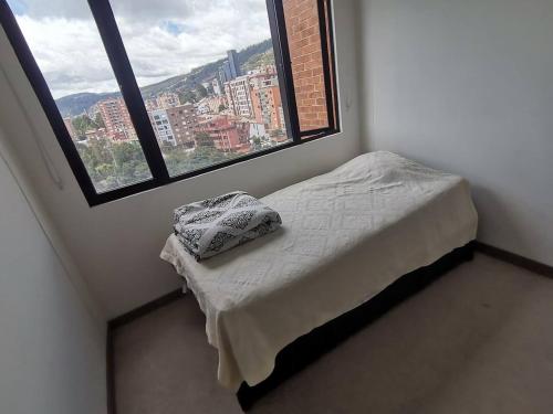 - un petit lit dans une chambre dotée d'une grande fenêtre dans l'établissement Apto nuevo de 67m2, con todas las comodidades, à Bogotá