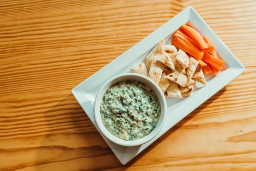 a plate of dip and crackers and vegetables on a table at Hotel Skyler Syracuse, Tapestry Collection by Hilton in Syracuse