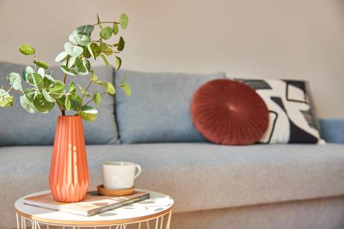 a blue couch with an orange vase on a table at Wonderful Panoramic View Apartment in Mukacheve