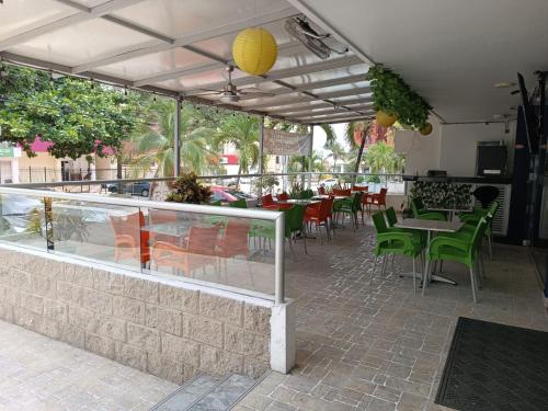 a restaurant with green chairs and tables and a counter at Hotel Prado 53 in Barranquilla