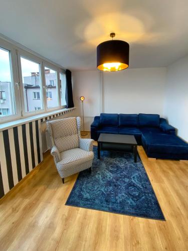 a living room with a blue couch and a chair at Apartament Panorama Centrum in Legnica