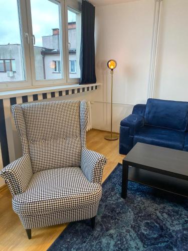 ein Wohnzimmer mit einem Stuhl und einem blauen Sofa in der Unterkunft Apartament Panorama Centrum in Legnica