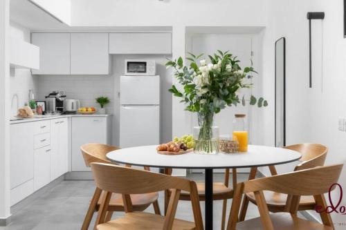 a white kitchen with a table with a vase of flowers at דירה משפחתית מפנקת 50 מטר מהים - By Edomlux in Eilat