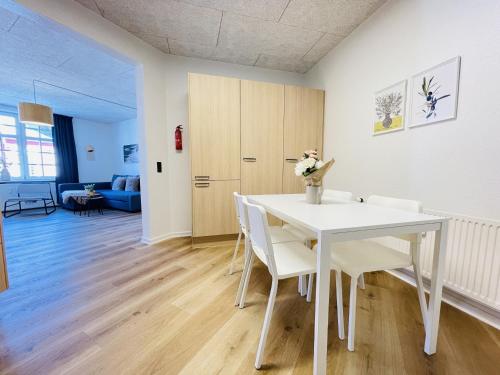 a white dining room with a white table and chairs at aday - Frederikshavn apartment on the Pedestrian street in Frederikshavn