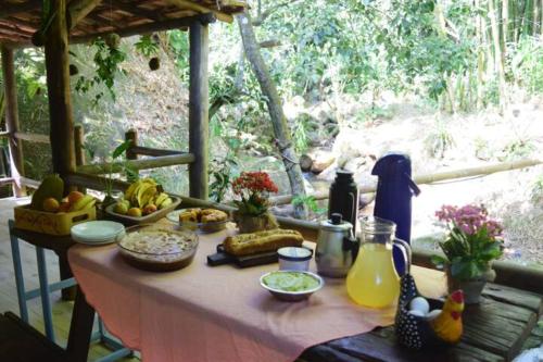 een tafel met eten en drinken voor een raam bij Pousada Portal Floresta Paraty in Paraty