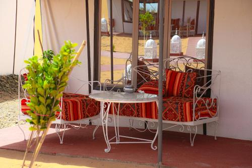 Merzouga Luxury Traditional Camp في مرزوقة: طاولة وكرسي للجلوس بجوار النافذة