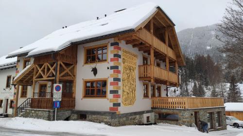 a house with a snow covered roof in the snow at Burglodge Fischerkeusche in Mauterndorf