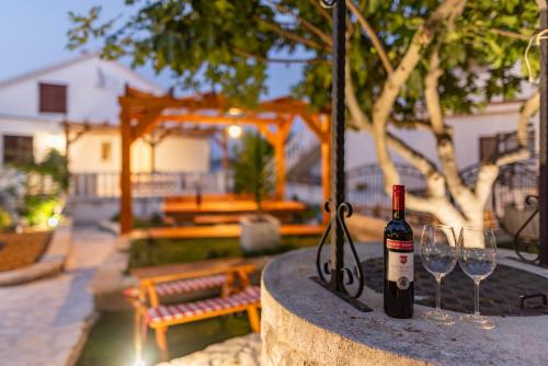 a bottle of wine and two wine glasses on a table at Home with a unique view in Preko