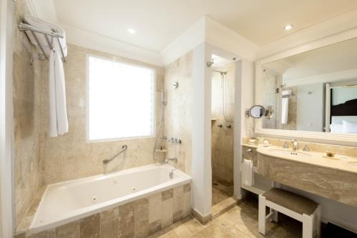 een badkamer met een bad, een wastafel en een spiegel bij Royal Hideaway Playacar All-Inclusive Adults Only Resort in Playa del Carmen
