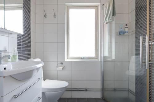 a white bathroom with a toilet and a sink at WHITE & BRIGHT Room in a shared apartment in Gothenburg