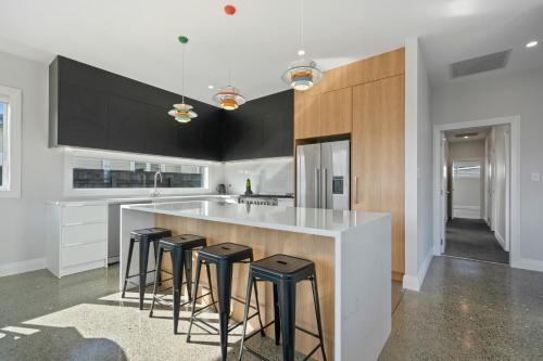 una cucina con sgabelli da bar e armadi in bianco e nero di Stylish Serenity - Martinborough Holiday Home a Martinborough