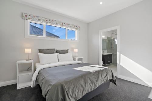- une chambre blanche avec un grand lit et une fenêtre dans l'établissement Stylish Serenity - Martinborough Holiday Home, à Martinborough