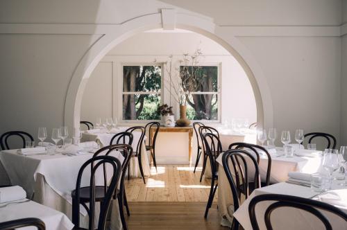 uma sala de jantar com mesas e cadeiras e uma janela em Links House em Bowral