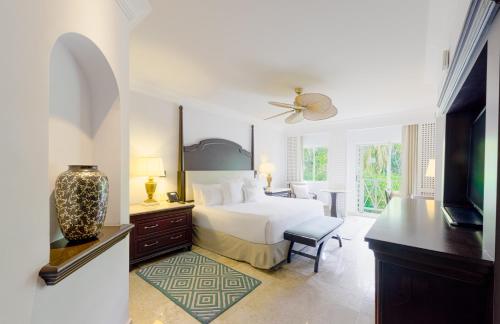 a white bedroom with a bed and a tv at Royal Hideaway Playacar All-Inclusive Adults Only Resort in Playa del Carmen