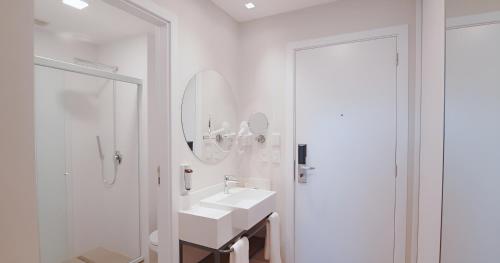 uma casa de banho branca com 2 lavatórios e um espelho em Wanderlust em Campos de Jordão