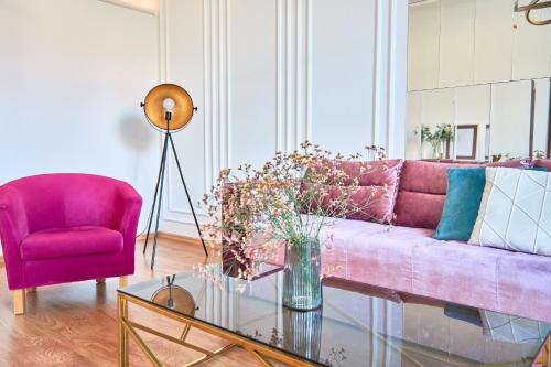 a living room with a pink couch and a red chair at Elegant Lux Apartment in central square in Mukacheve