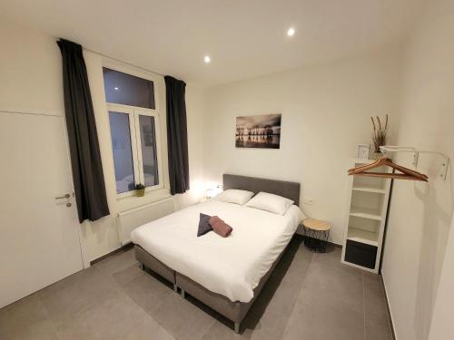 a bedroom with a white bed and two windows at Family apartment on the ground floor with terrace - Panne A Côte in De Panne
