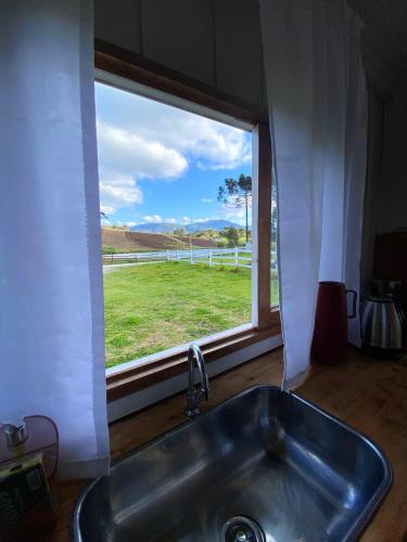 eine Küchenspüle mit einem Fenster mit Blick auf ein Feld in der Unterkunft Casa de temporada - Recanto da invernada in Urubici