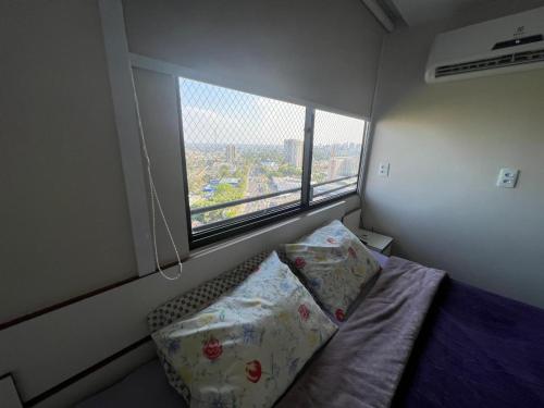 een kleine slaapkamer met een bed en een groot raam bij Apartamento em Manaus in Manaus