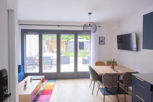 d'un salon avec une table, des chaises et une porte coulissante en verre. dans l'établissement Le Saint-Germain - Porte d'Orléans - Cité Universitaire Paris 14, à Gentilly