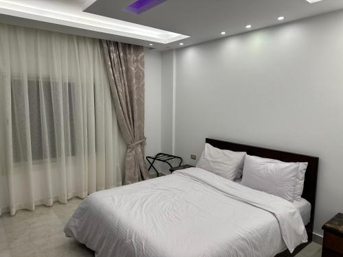 een slaapkamer met een wit bed en een raam bij Le Royal Residence 4 in Caïro