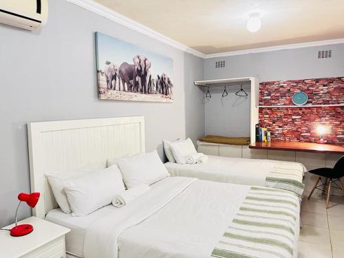 1 dormitorio con 2 camas y pared de ladrillo en Decent Stay, en Durban