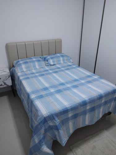 una cama con una manta de cuadros azul y blanco en Apto novo e bem localizado em Porto Belo - SC, en Porto Belo