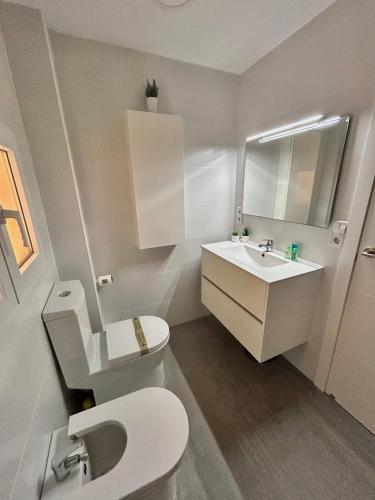 a bathroom with a white toilet and a sink at Mareny de Barraquetes in Mareny Blau