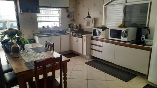 a kitchen with a table and a microwave oven at Casa do Roberto in Jaraguá do Sul